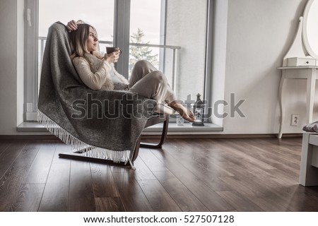 Woman drinks coffee and relax on vintage sofa at home near the window. Interior decoration in living room