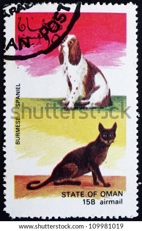 OMAN - CIRCA 1972: a stamp printed in the Oman shows Burmese Cat and Spaniel Dog, circa 1972