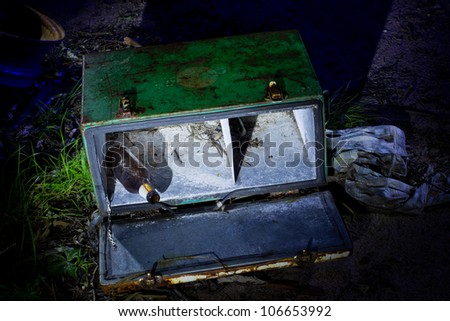 An old ice box with beer bottle falling out lightpainted at night