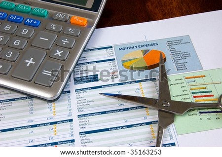 Budget spreadsheet with calculator, scissors, stapler, and paper clips on a wooden desk
