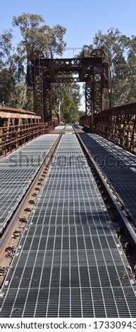 Detail of the railway track converging towards a vanishing point after the bridge end