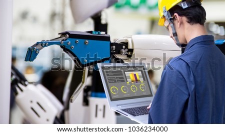Industry 4.0 Robot concept .Engineers use laptop computers for machine maintenance, automation tools, robot arm at the factory.