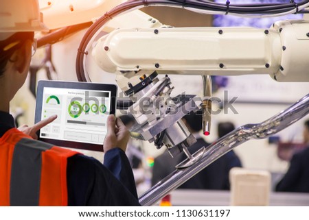 Industry 4.0 Robot concept .Engineers use laptop computers for machine maintenance, automation tools, .Close up of a robot arm in a car manufacturing department.