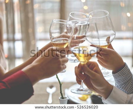Alcohol cheers clinking glasses of champagne in hands on bright lights background