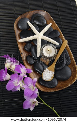spa salt in spoon bowl and stones with candle and starfish with branch orchid on mat