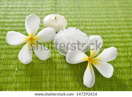 White frangipani flower with salt in bowl ,candle on green straw mat