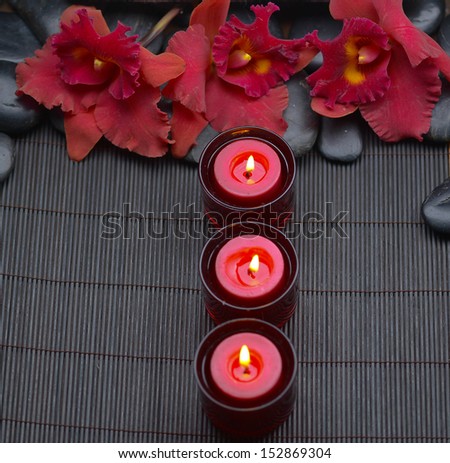 Spa setting-red orchid with row of candle and zen stones on mat