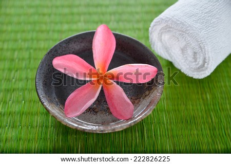 frangipani flower in bowl with towel on green mat