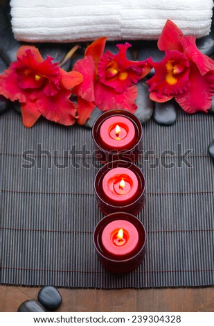 Three candle with red orchid with towel, stones at spa