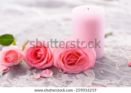 rose petals and three rose with candle on lace