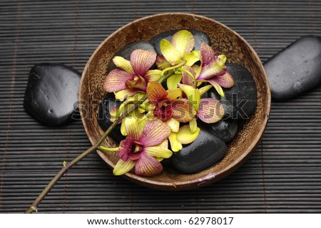 Wooden bowl of orchid and stones on bamboo stick straw mat