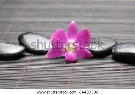 Pink orchid and zen Stones on bamboo stick straw mat