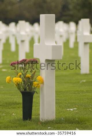 Singled out white cross with flowers on Margraten military cemetery in The Netherlands.