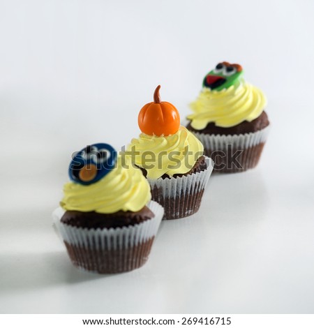 A close up of a chocolate cupcake, covered with Halloween decoration object on top, a little whipped cream and top with a fresh and luscious