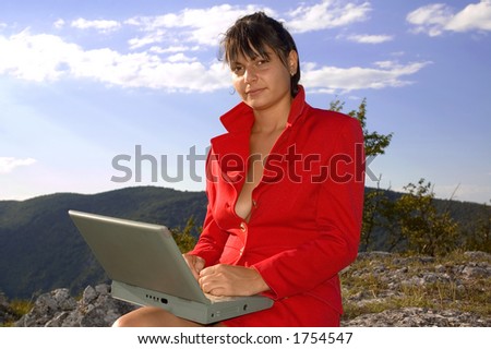 Business woman in red clothes with laptop at top of mountains