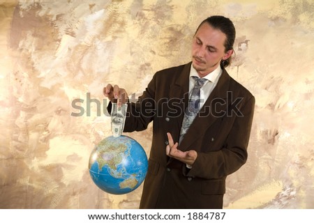 Businessman holding globe with money - Parody on earning money