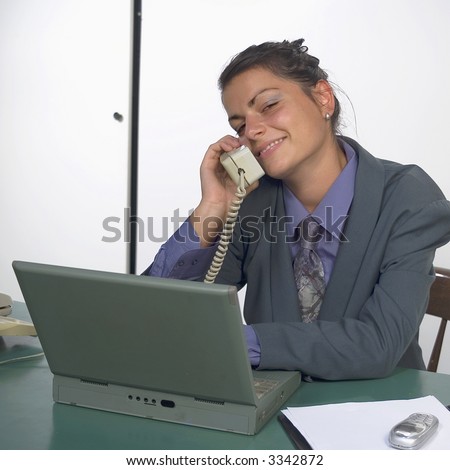 Businesswoman cell on phone at the office with laptop and fax machine