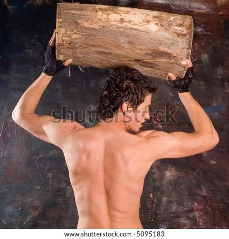 Muscular builder man training his body with log