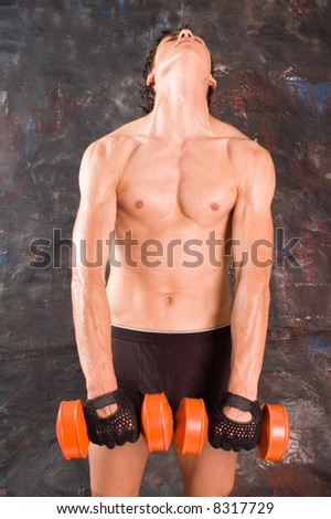 Muscular builder man training his body with dumbbell