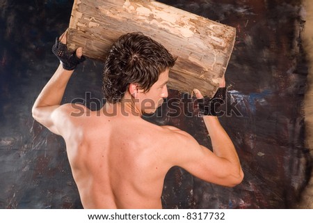 Muscular builder man training his body with log