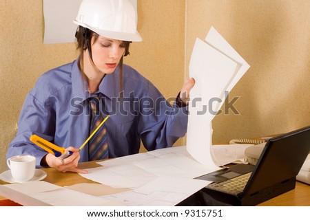 Woman architect with helmet on head and arch project at table