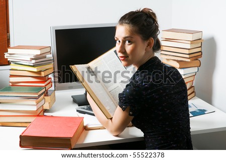 Young beautiful student learning at her room with pile of books
