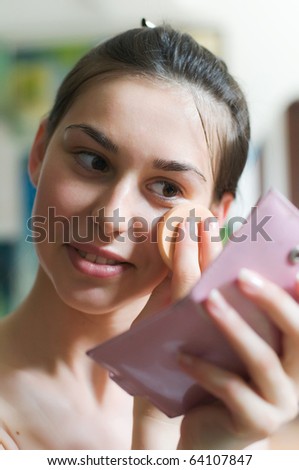 Young pretty woman applying powder on her face