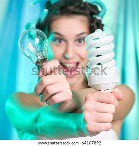 Woman holding and looking at energy saving compact fluorescent lightbulb and classical bulb