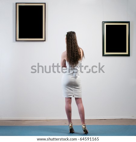 Woman standing inside a gallery and looking at two black pictures Woman standing inside a gallery and looking at two black pictures