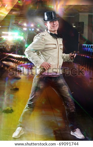 Disc jockey dancing with microphone and headphones  at night club