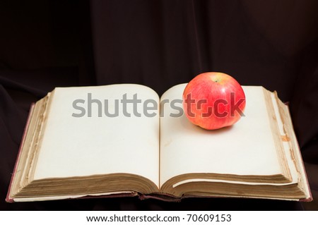 Open blank antique book with apple on it