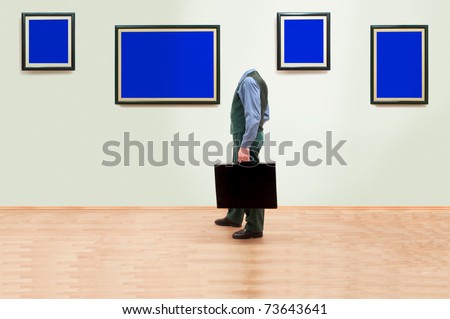 One man without head standing and looking at blank blue frames in an art gallery.