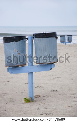 Trash cans on a public beach with selective focus on the two trash cans in the foreground of the photograph.  Taken in Atlantic Beach, North Carolina