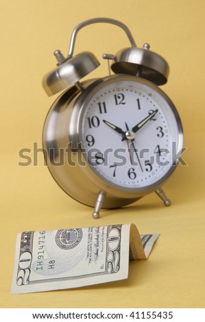 In today\'s world time is money.  Alarm clock and American paper currency isolated on a yellow background.