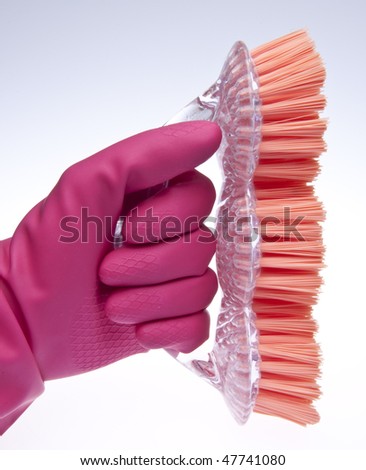 Pink gloved hand with brush for spring cleaning.
