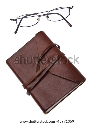 Old leather journal with simple black glasses isolated on white with a clipping path.