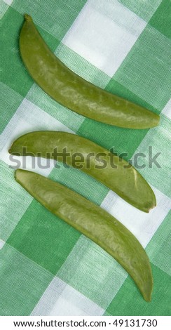 Sugar snap peas on a bright green picnic tablecloth.