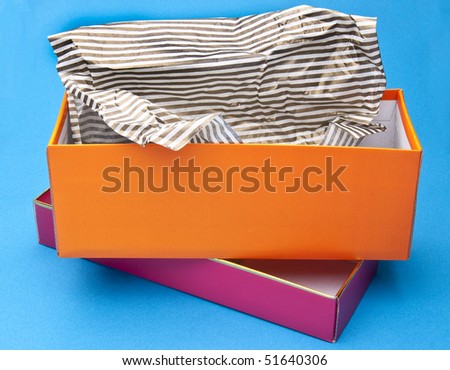 Orange and Pink Fancy Gift Box Opened with Striped Tissue Paper on a Blue Background.