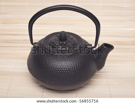Simple Black Tea Pot on a Bamboo Mat Background.