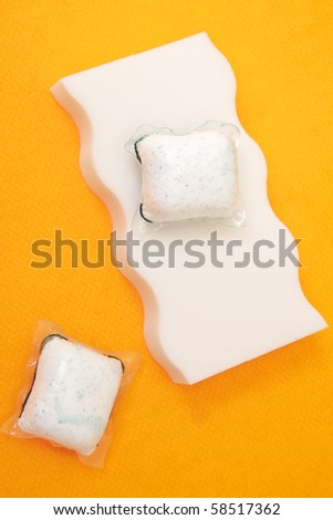 Sponge and Powdered Dish Soap on a Vibrant Orange Background.