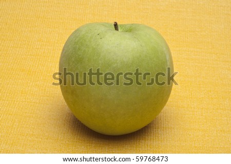 Green Granny Smith Apple on a Yellow Background.