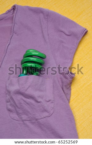 Green Compact Fluorescent Light Bulb in a Shirt Pocket on a Yellow Background.  Eco Friendly Concept.