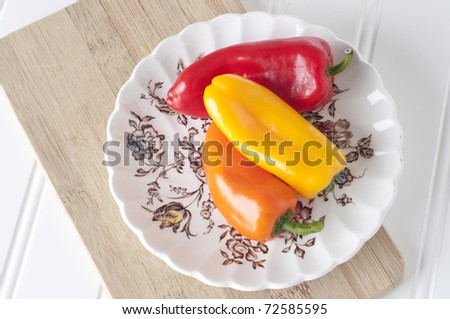 Three Sweet Peppers on Delicate Floral Plate with Wooden Board.