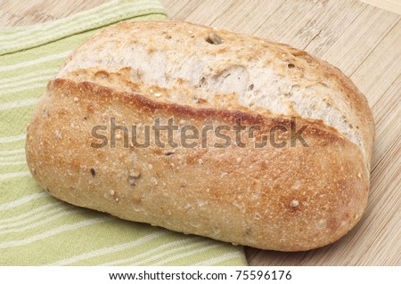 Loaf of Crusty Whole Wheat Bread on Wooden Block.