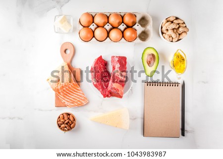 Ketogenic low carbs diet concept. Healthy balanced food with high content of healthy fats. Diet for the heart and blood vessels. Organic ingredients, white background, copy space top view, notepad
