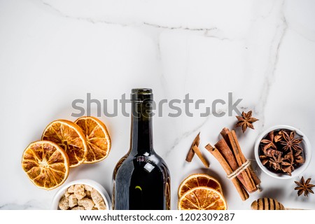 Ingredients for traditional autumn drink, mulled wine cocktail - red wine, stale oranges, cane sugar, honey, cinnamon, spices, anise, on white marble background, top view space for text