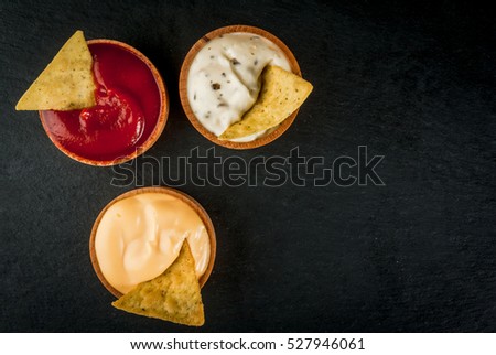 Snack for party, chips, nachos with sauces: tomato (ketchup), cheese and mayonnaise (tartar), top view, copy space