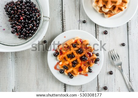 Homemade breakfast. Fresh Belgian waffles with summer berries and currant jam. On a white rustic wooden table.