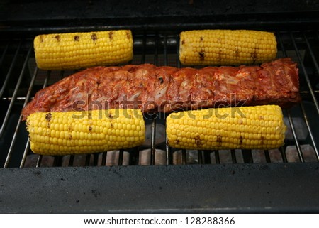 A large piece of meat and may four-piston on a gas Grill
