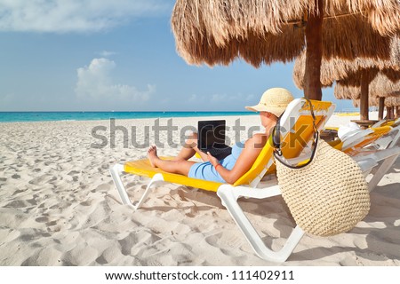 Woman with laptop relaxing on the deckchair at the Caribbean sea